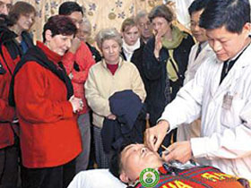 foreign visitors are watching the performance of a facial acupuncture treatment in our acupuncture c